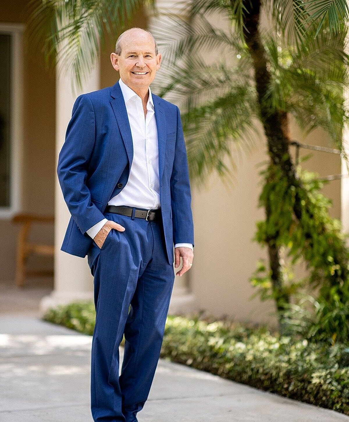 Man in blue suit smiling outdoors.