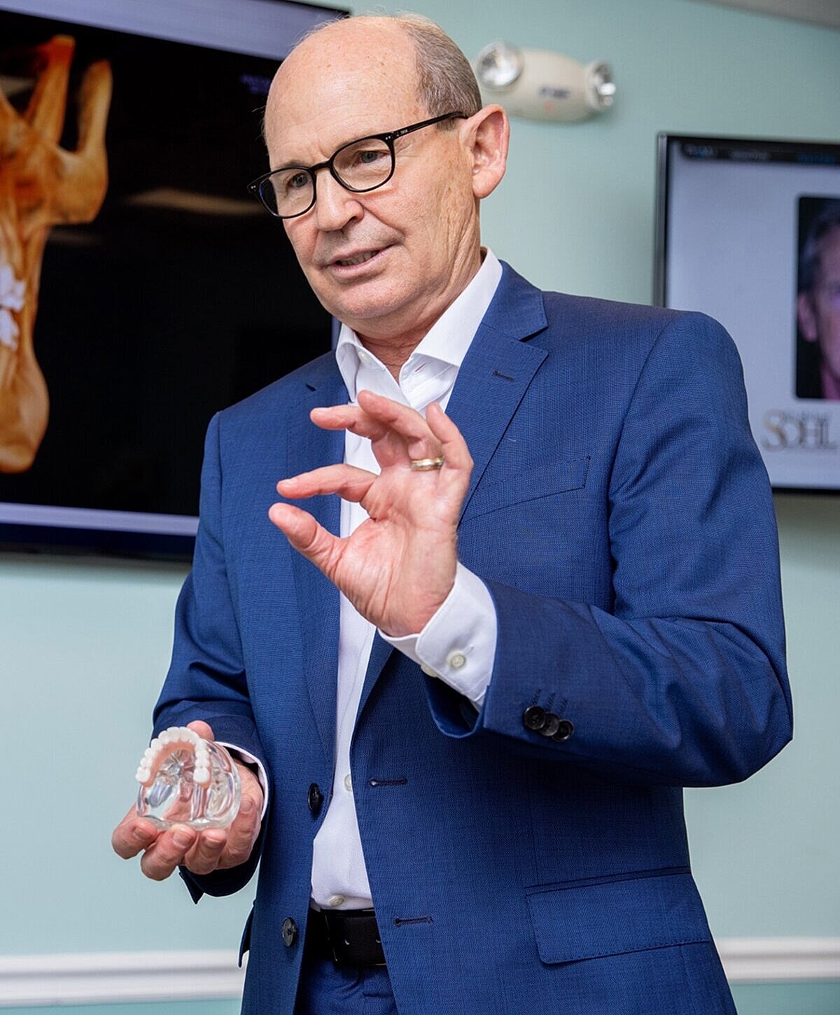 Professional speaking with dental model in hand.