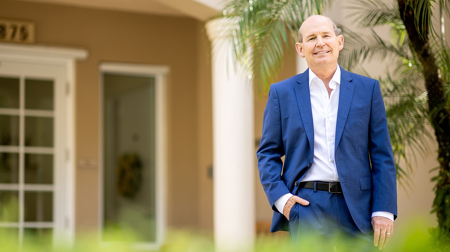 Man in a blue suit standing outside a house.