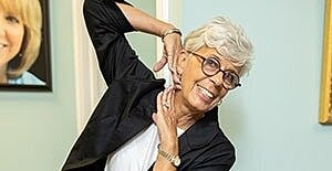 Smiling older woman posing playfully indoors.