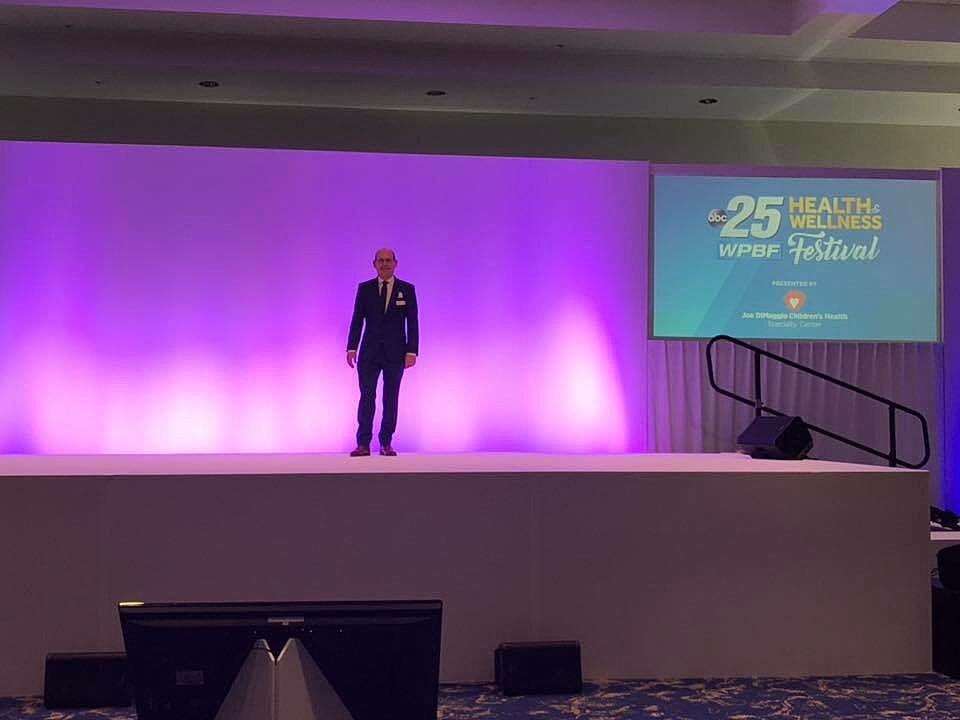 Speaker on stage at wellness festival event.