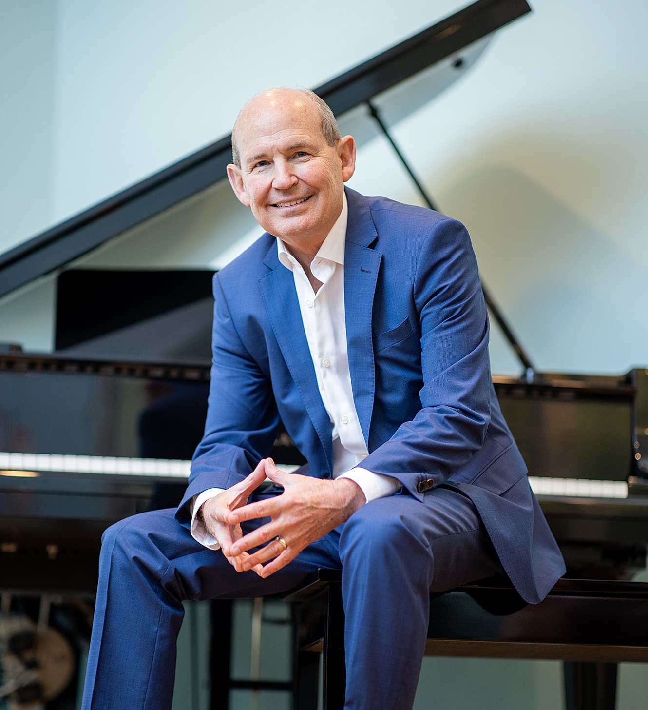 Man in suit sitting by piano.