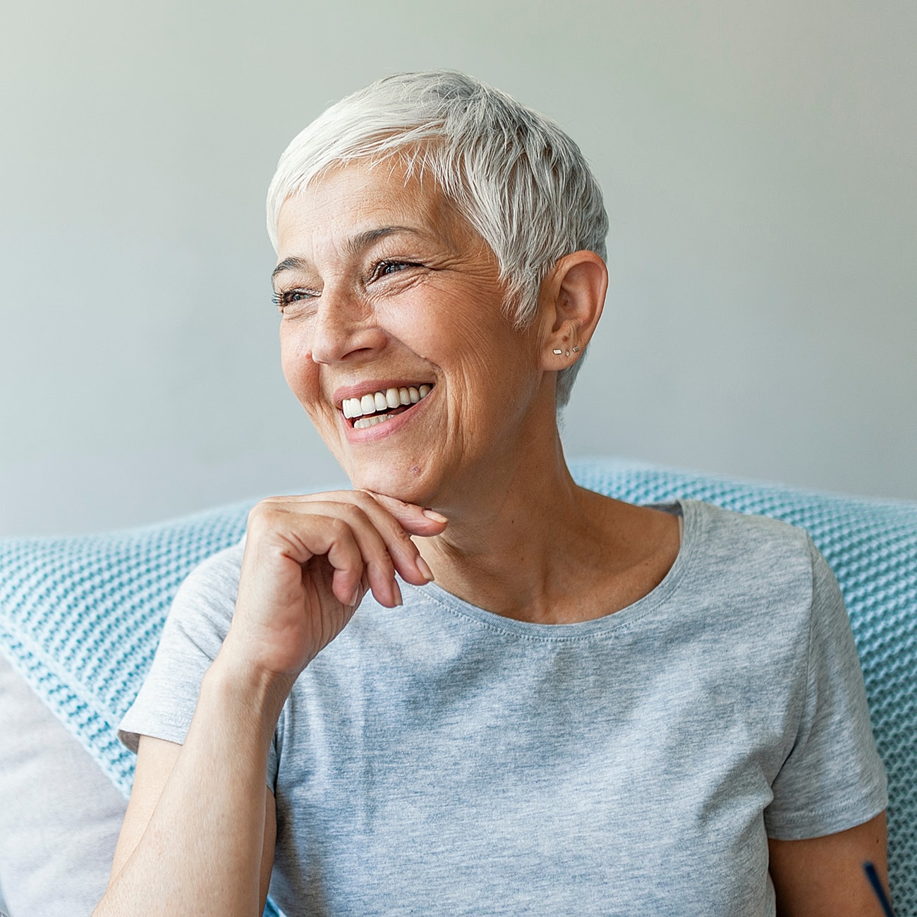 Smiling older woman in casual gray shirt.