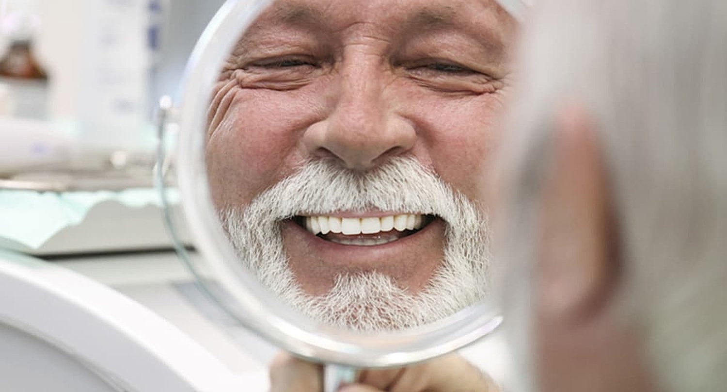 Smiling man looking in a mirror.