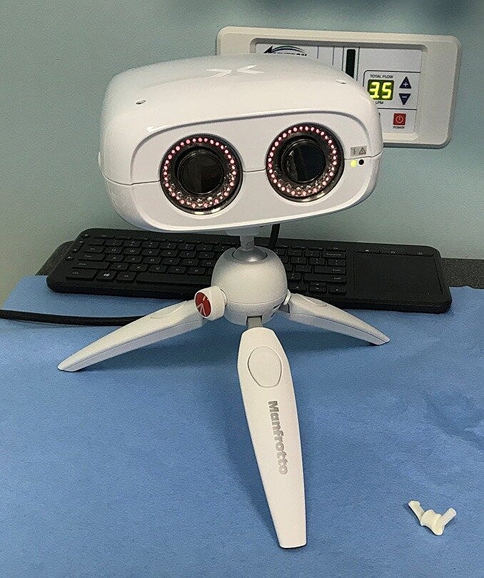 White robot with tripod legs and dual cameras.