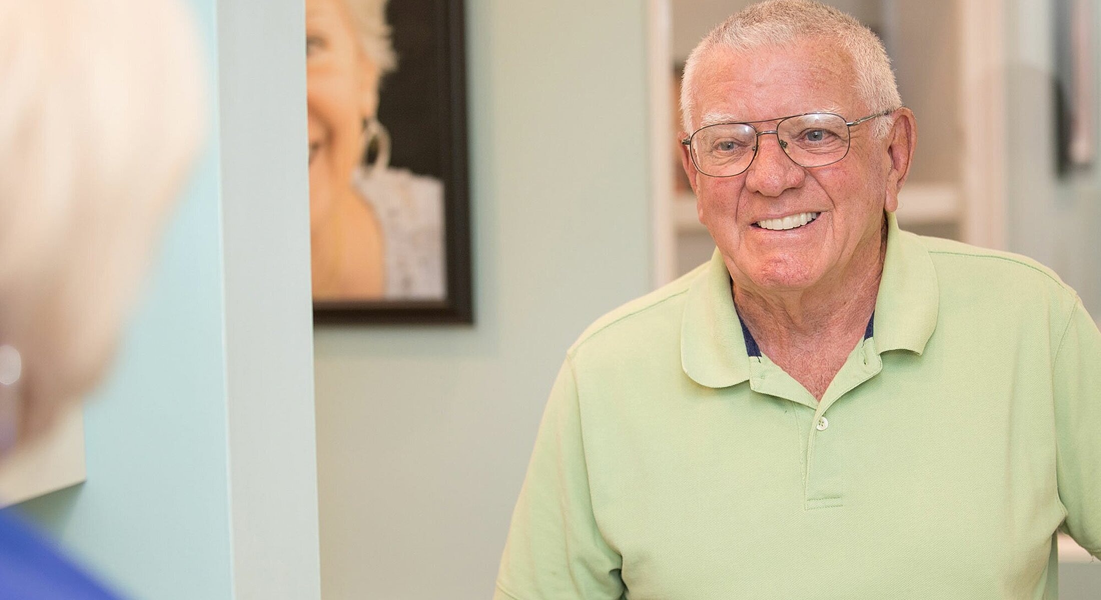 Smiling elderly man in green shirt.
