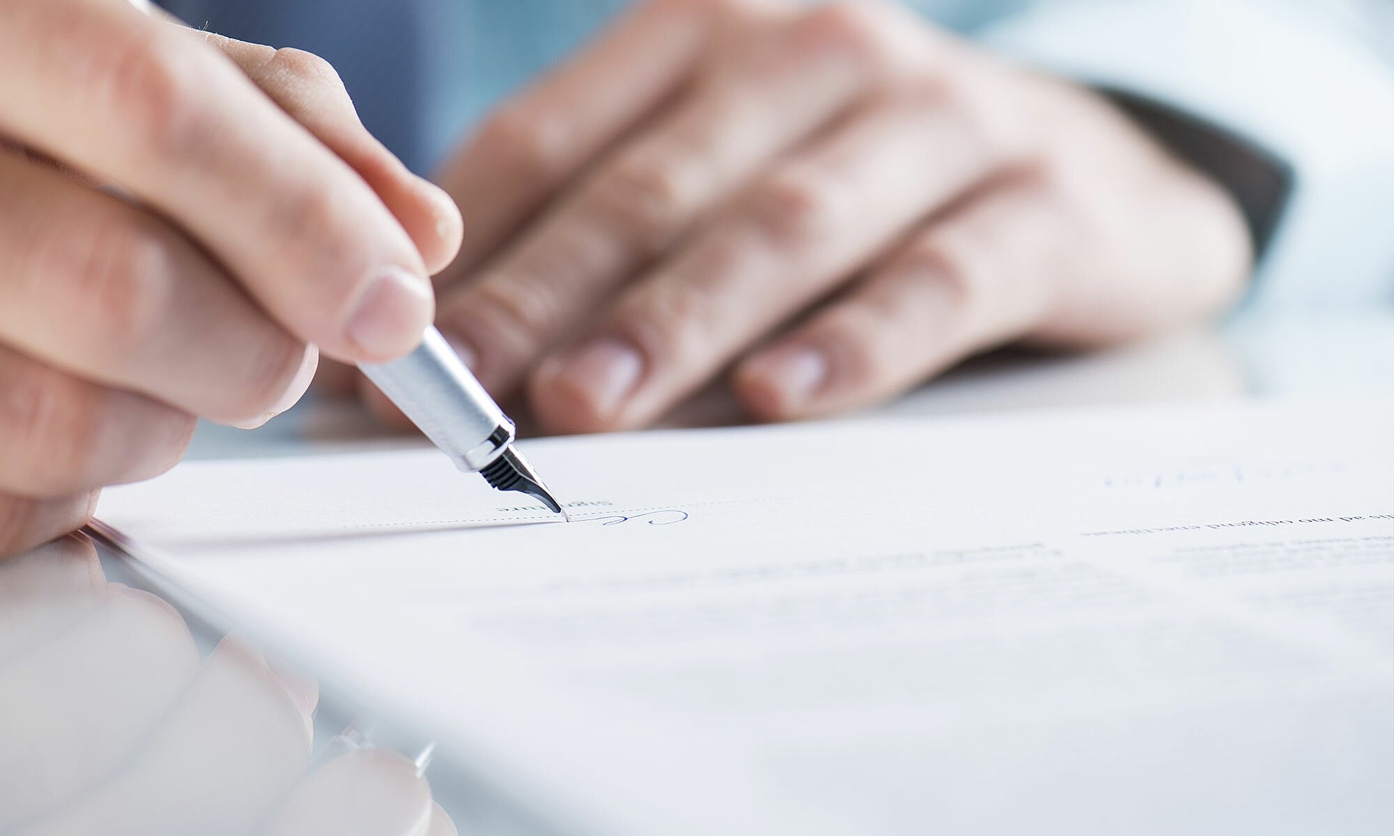 Person signing a document with a pen.