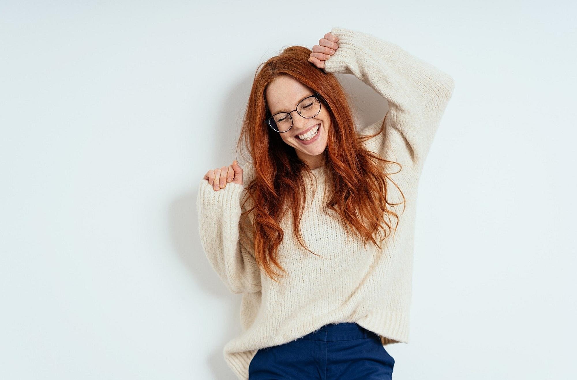 Woman smiling in cozy sweater against white background.