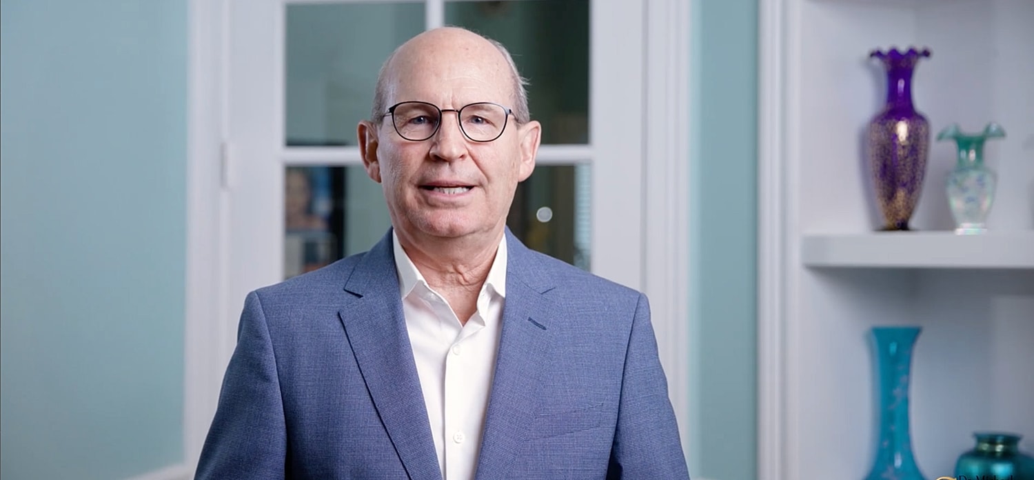 Man standing outdoors promoting dental implants steps.