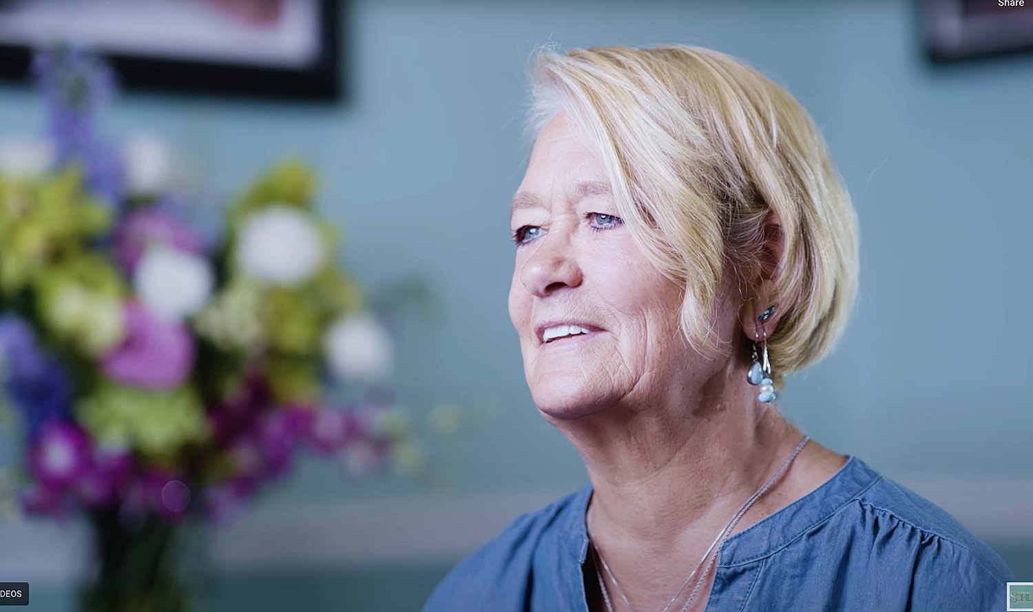 Man in a cowboy hat smiling warmly indoors.