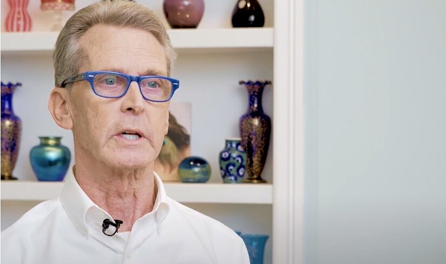 Man in a cowboy hat smiling warmly indoors.